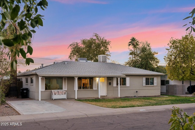 ranch-style home with a porch, fence, a front lawn, and roof with shingles