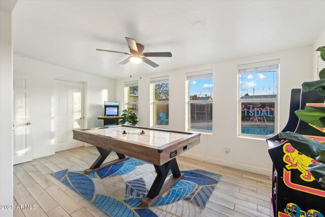 rec room with light wood-style flooring, a ceiling fan, and a wealth of natural light