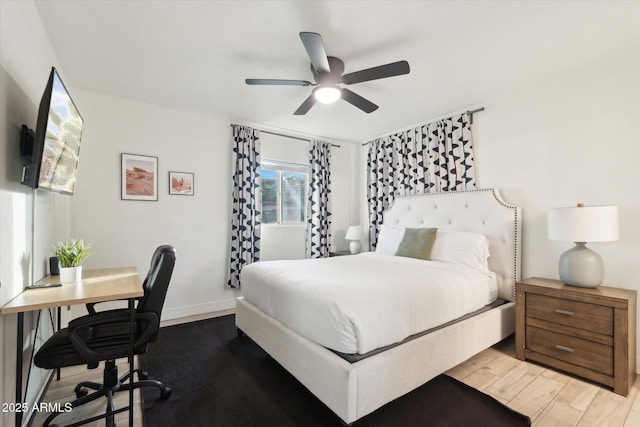 bedroom with a ceiling fan, wood finished floors, and baseboards