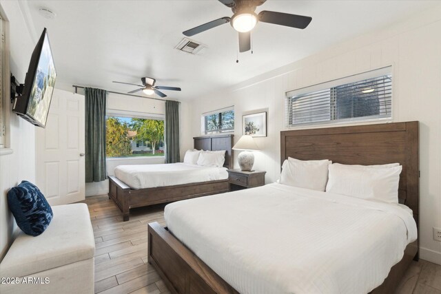 bedroom with light wood finished floors, visible vents, and ceiling fan