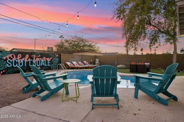 pool at dusk with a patio area and a fenced backyard