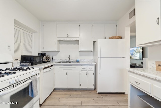 kitchen with light wood finished floors, white cabinets, white appliances, and a sink