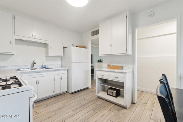 kitchen with white appliances, white cabinets, light wood-type flooring, and a sink