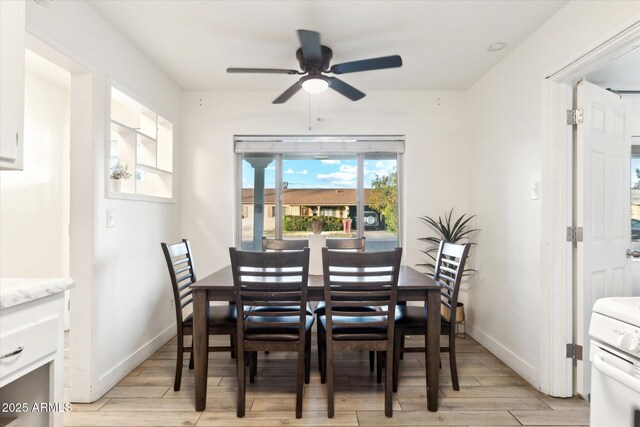 dining room with ceiling fan, baseboards, and light wood-style floors