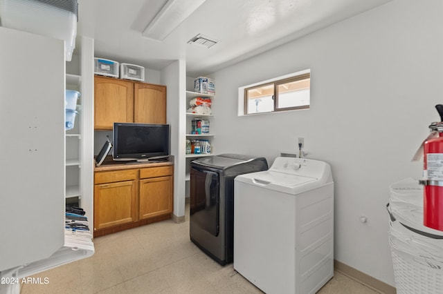 clothes washing area with cabinets and washer and clothes dryer