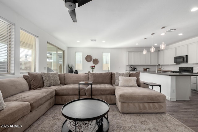 living room with ceiling fan, sink, and hardwood / wood-style floors