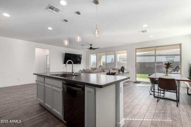 kitchen featuring a center island with sink, ceiling fan, dishwashing machine, hanging light fixtures, and sink