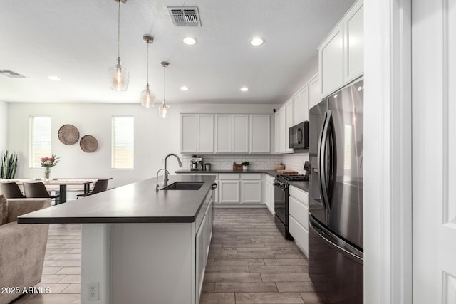 kitchen featuring stainless steel fridge, sink, gas stove, and white cabinetry