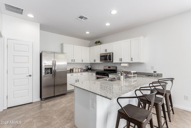 kitchen featuring light stone countertops, stainless steel appliances, kitchen peninsula, a kitchen bar, and white cabinets