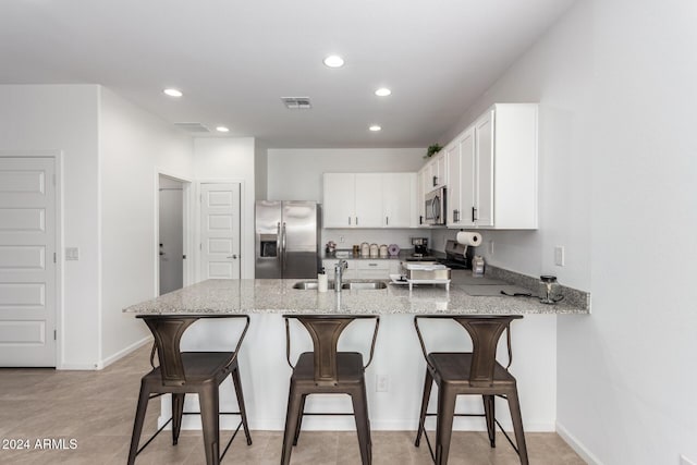 kitchen featuring kitchen peninsula, appliances with stainless steel finishes, a breakfast bar, sink, and white cabinets