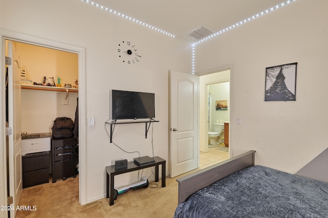 bedroom featuring light carpet and a walk in closet