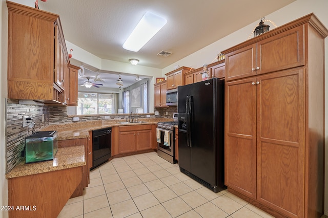 kitchen with backsplash, light stone countertops, sink, and black appliances