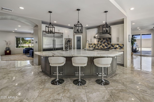 14749 E Pecos Rd, Gilbert, AZ 85295 - kitchen with visible vents, decorative backsplash, marble finish floor, wall chimney range hood, and appliances with stainless steel finishes