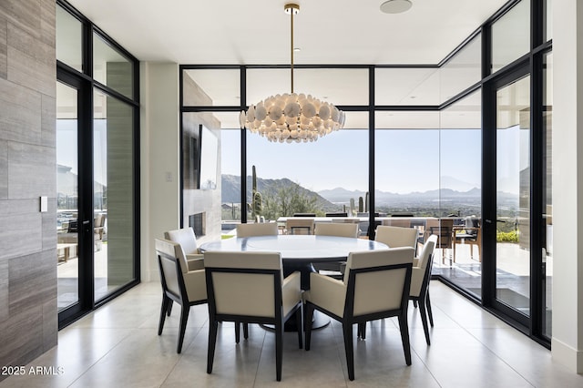 dining area featuring an inviting chandelier, a wall of windows, and a mountain view