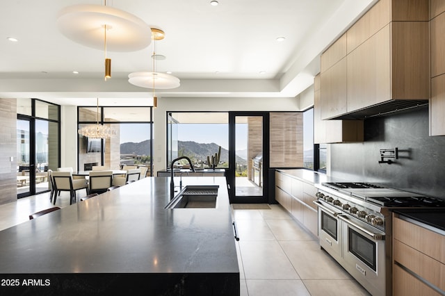 kitchen with sink, light brown cabinets, a mountain view, pendant lighting, and range with two ovens