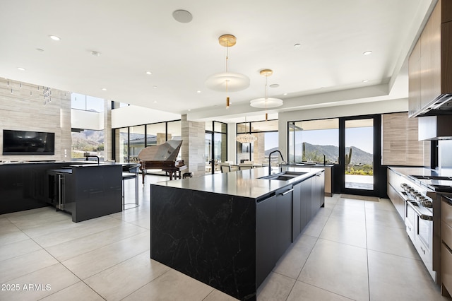 kitchen featuring sink, a mountain view, a kitchen island with sink, and hanging light fixtures