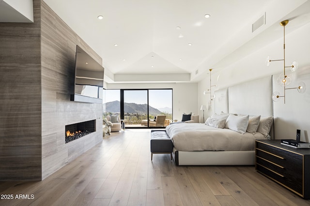 bedroom featuring a tiled fireplace, access to exterior, and light wood-type flooring