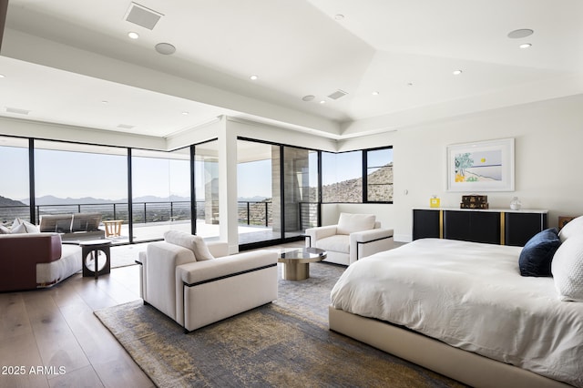 bedroom with hardwood / wood-style flooring, lofted ceiling, a mountain view, and access to outside