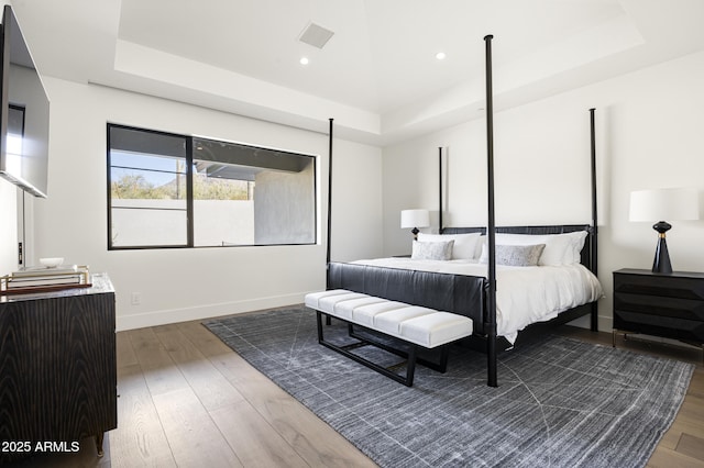 bedroom with hardwood / wood-style flooring and a raised ceiling