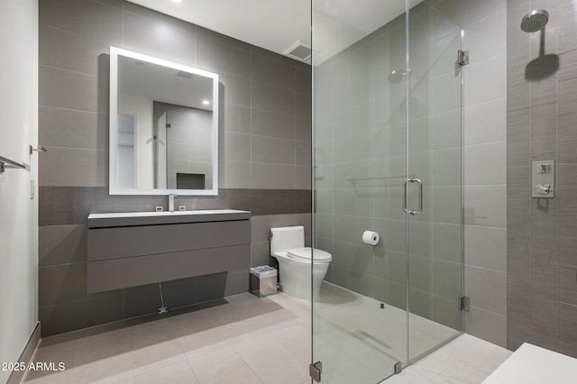 bathroom with tile walls, vanity, an enclosed shower, toilet, and tile patterned floors