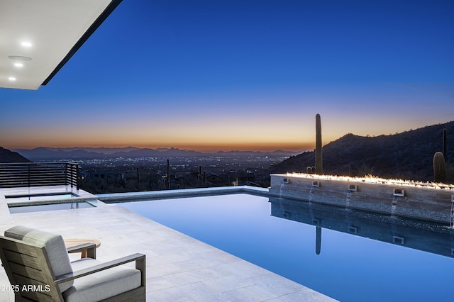 pool at dusk featuring a mountain view