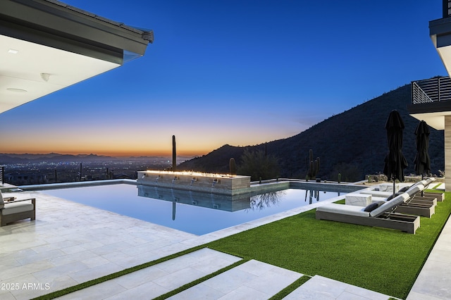 pool at dusk with a mountain view and a patio