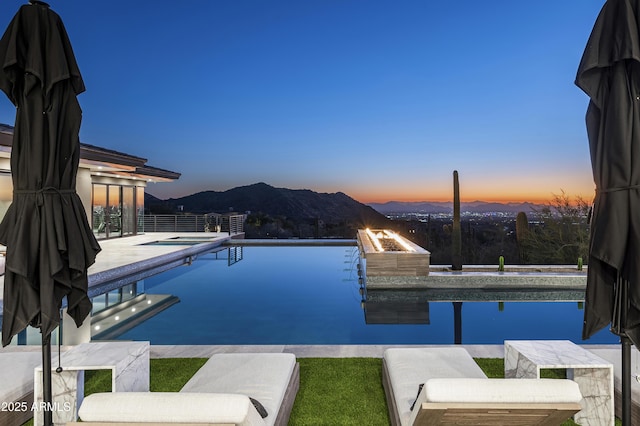 pool at dusk featuring an outdoor fire pit and a mountain view