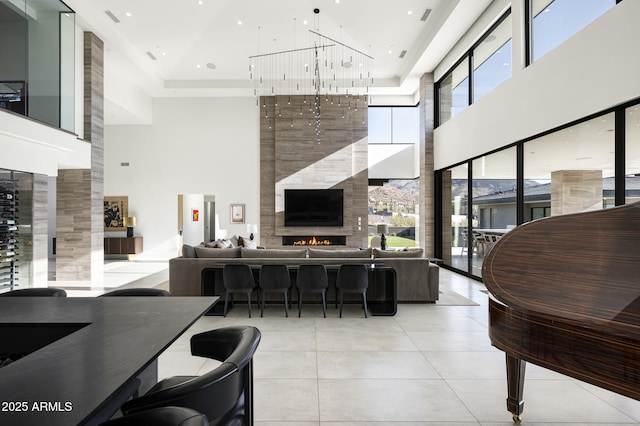 interior space featuring light tile patterned floors, a towering ceiling, a fireplace, and a raised ceiling