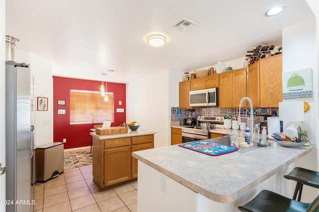 kitchen featuring pendant lighting, kitchen peninsula, stainless steel appliances, and light tile patterned floors