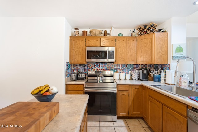 kitchen featuring tasteful backsplash, sink, light tile patterned flooring, and appliances with stainless steel finishes