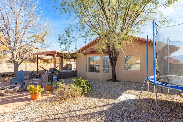 back of property featuring a patio area and a trampoline