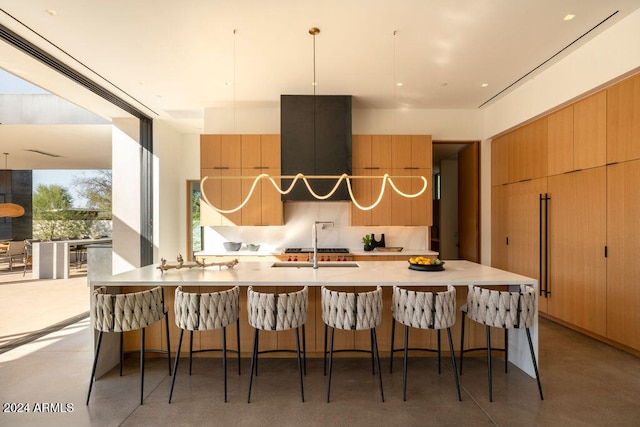 kitchen featuring a kitchen bar, concrete floors, decorative light fixtures, and exhaust hood