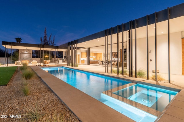 pool at night featuring a patio and an in ground hot tub