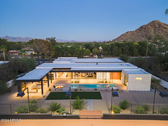 back of property featuring a mountain view, a swimming pool with hot tub, and a patio area