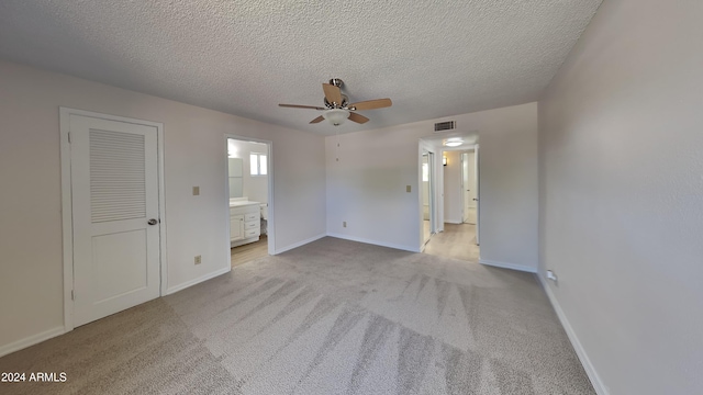 unfurnished bedroom featuring ceiling fan, connected bathroom, a closet, and light colored carpet