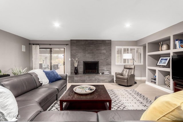 living room featuring a fireplace, built in shelves, and hardwood / wood-style floors