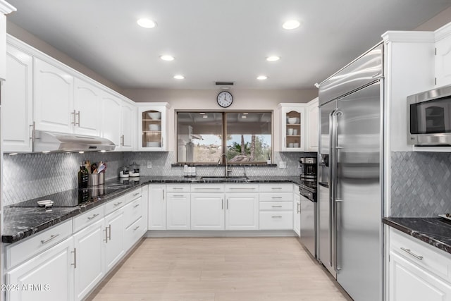 kitchen with sink, stainless steel appliances, light hardwood / wood-style flooring, dark stone counters, and white cabinets