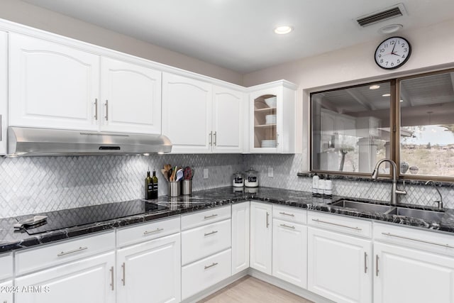 kitchen with white cabinetry, sink, dark stone countertops, black cooktop, and decorative backsplash