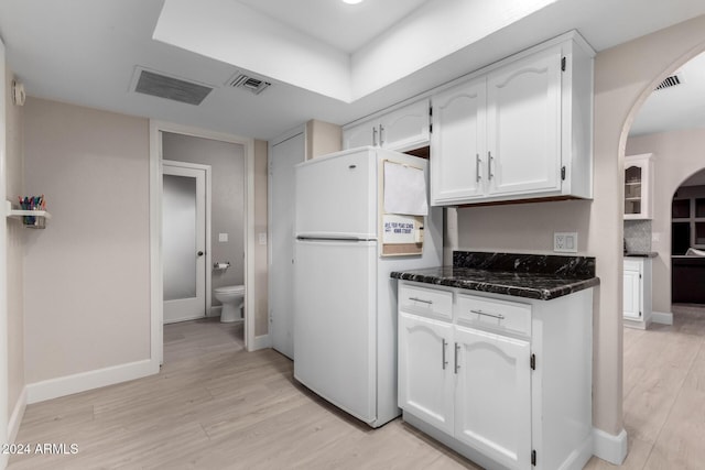 kitchen featuring backsplash, white fridge, white cabinetry, and light hardwood / wood-style flooring