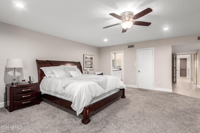 bedroom featuring ceiling fan, light colored carpet, and connected bathroom