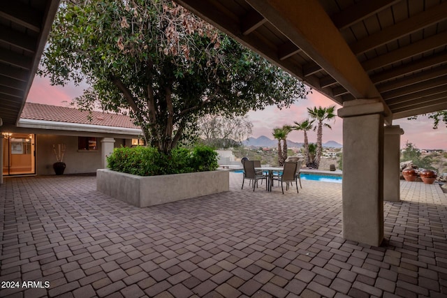 patio terrace at dusk featuring a fenced in pool