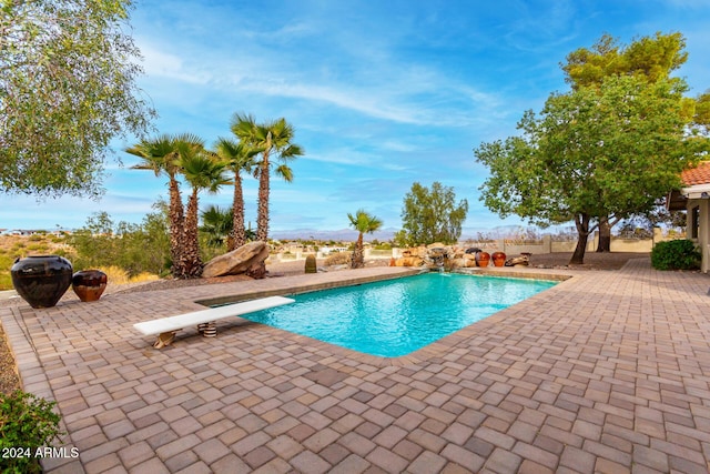 view of swimming pool featuring a diving board and a patio