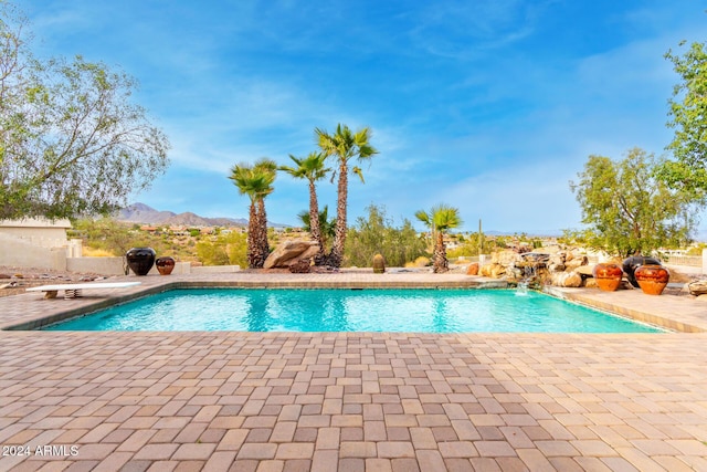 view of swimming pool featuring a mountain view, pool water feature, and a patio area