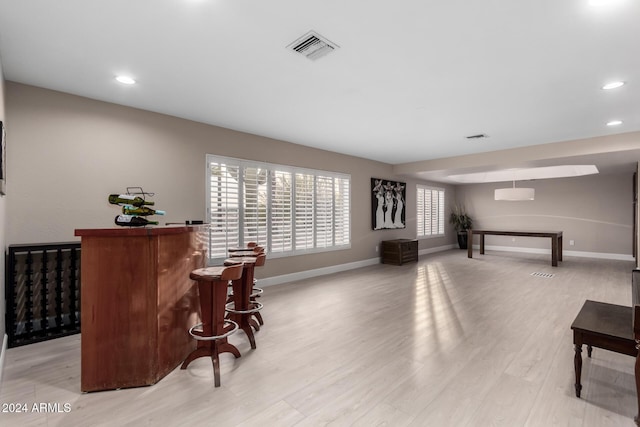 interior space with light wood-type flooring and indoor bar