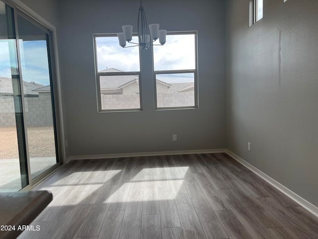 unfurnished dining area with hardwood / wood-style flooring and a chandelier