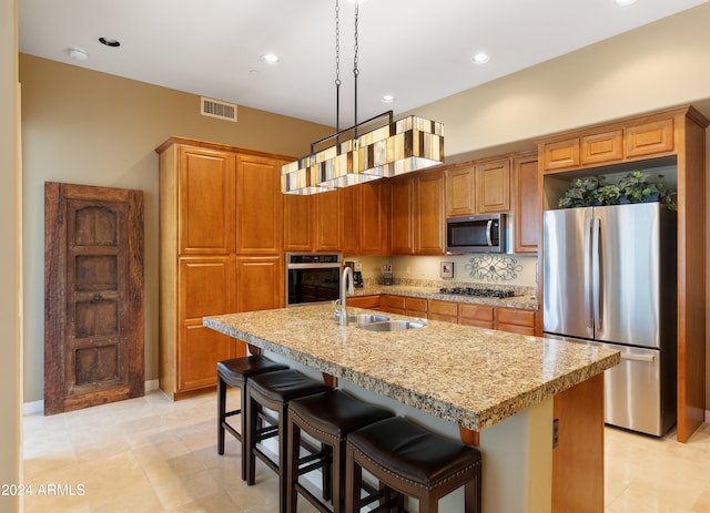 kitchen featuring an island with sink, hanging light fixtures, and stainless steel appliances