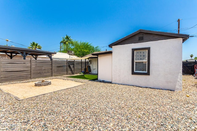 5044 N 18th Ave, Phoenix, AZ 85015 - view of side of home with a fire pit, stucco siding, a fenced backyard, and a patio area