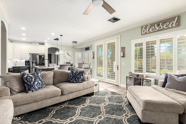 597 S 221st Dr, Buckeye, AZ 85326 - living area with ceiling fan, arched walkways, ornamental molding, light wood-type flooring, and recessed lighting