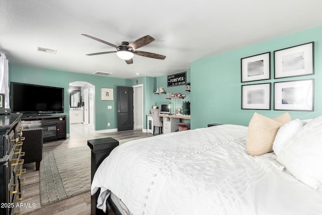 597 S 221st Dr, Buckeye, AZ 85326 - bedroom with arched walkways, wood finished floors, baseboards, ceiling fan, and ensuite bath