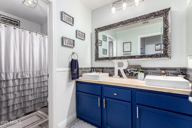 597 S 221st Dr, Buckeye, AZ 85326 - full bath with double vanity, a wainscoted wall, and curtained shower